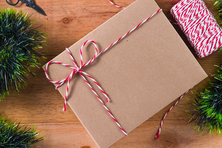 craft gift box tied  with red and white rope on wooden table, top view