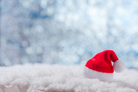 Christmas Santa Claus hat on white snow, beautiful bokeh backgroundの写真素材