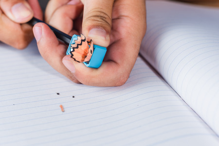 a man sharpening pencil on white lines paper book page