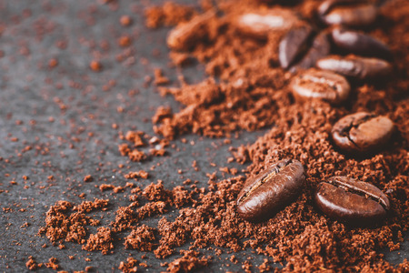 close-up of coffee powder and beans splash on black wooden boardの写真素材