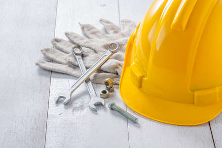 yellow safety helmet and tools on white wooden tableの写真素材