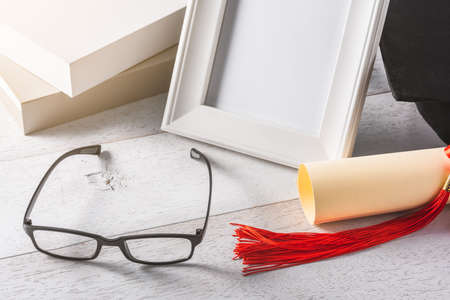 Close-up of glasses and education or graduation equipment background on wooden white table, congratulation conceptの写真素材