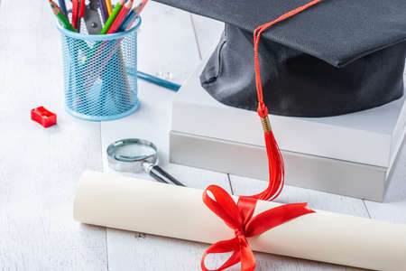 diploma tied with red ribbon on white wooden tableの写真素材