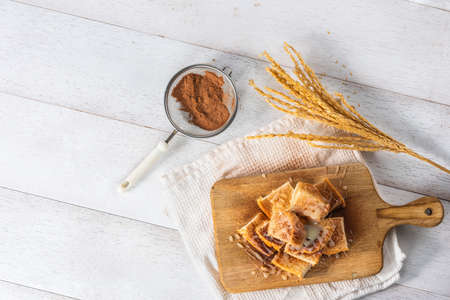 pile of bread poured with sweetened condensed milk and chocolate powder on wooden cutting board, top viewの写真素材