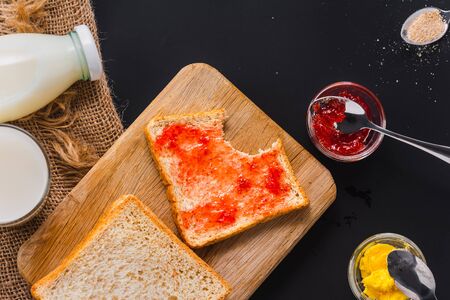 strawberry jam bread with bite mark on wooden board, top viewの写真素材