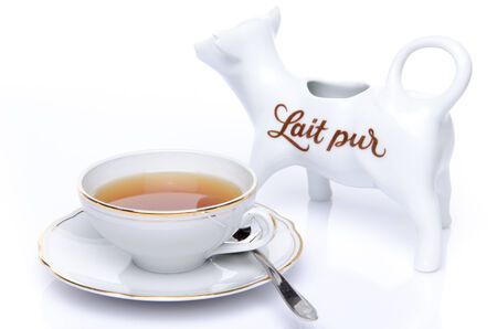 A cup of tea with a milk jug, isolated on whiteの写真素材