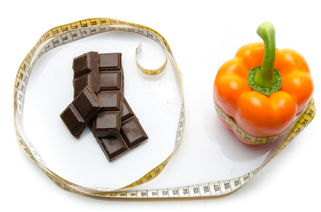 Measuring tape around a pepper and chocolate, isolated on whiteの写真素材