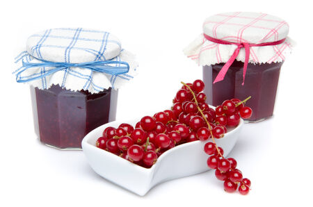 Redcurrants in a small dish and two jars of redcurrant jam, isolated on whiteの写真素材