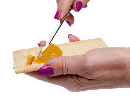 Woman's hand spreading orange marmalade on a toast, isolated on whiteの写真素材