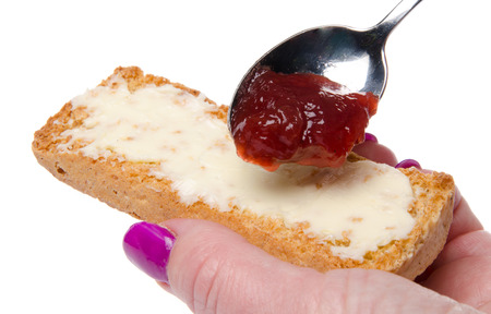 Woman's hand putting strawberry jam on a toastの写真素材