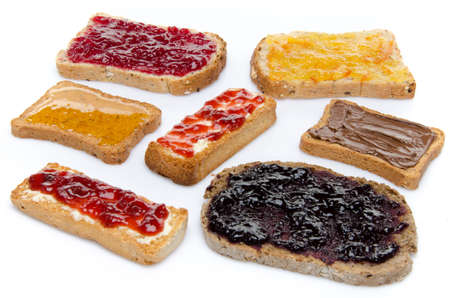 Some toasts with jams, honey and hazelnut spread, isolated on whiteの写真素材