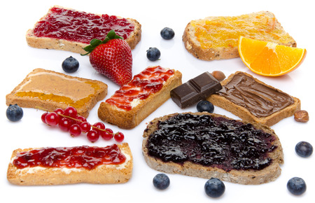 Some toasts with jams, honey and hazelnut spread, isolated on whiteの写真素材