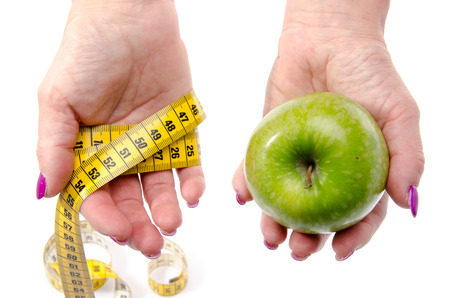 Woman s hands holding an apple and a tape measure, isolated on whiteの写真素材