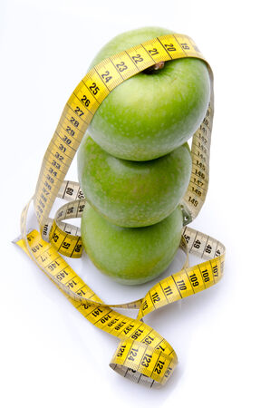 Stacked apples with a tape measure, isolated on whiteの写真素材