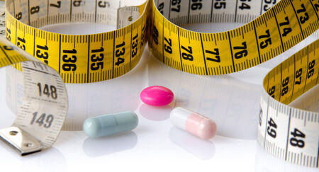 Measuring tape with pills, isolated on whiteの写真素材