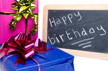 Happy birthday written on a slate blackboard with gifts, isolated on whiteの写真素材