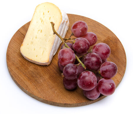 Soft cheese with grapes on a wooden board, isolated on whiteの写真素材