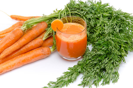 Composition with a glass of carrot juice and fresh carrots, isolated on whiteの写真素材