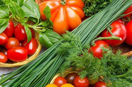 Composition of different varieties of tomatoes in baskets with herbsの写真素材