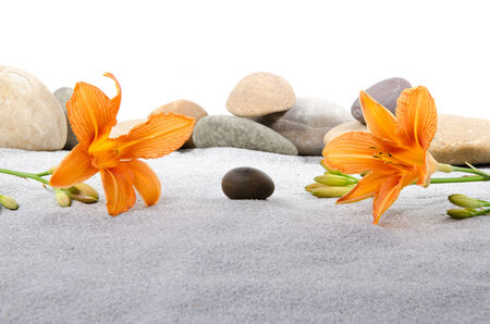 Composition with pebble stones and orange lily flowers on gray sandの写真素材