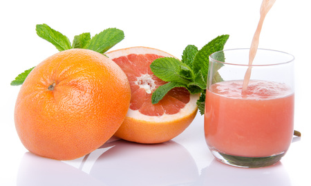 Grapefruit juice poured into a glass, isolated on whiteの写真素材