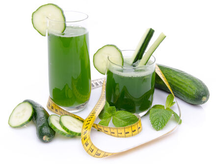 Composition with cucumber juice, fresh cucumbers and a tape measure, isolated on whiteの写真素材