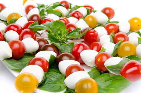 Plate of cherry tomatoes and mozzarella on skewers, isolated on whiteの写真素材