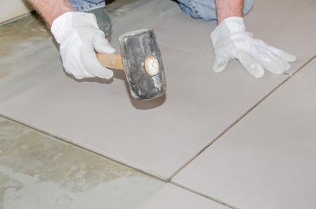 Laying floor tiles, tiler using a rubber malletの写真素材