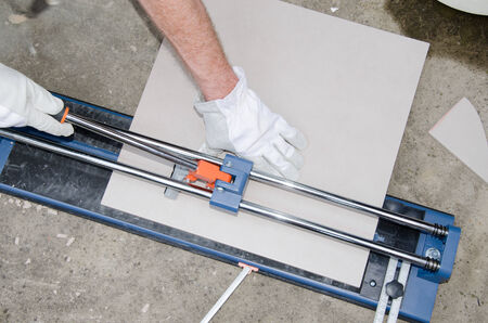 Laying floor tiles, tiler using a tile cutterの写真素材