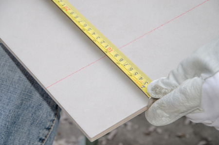 Laying floor tiles, tiler measuring tile before cuttingの写真素材