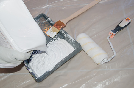 Painter pouring white paint in a paint trayの写真素材