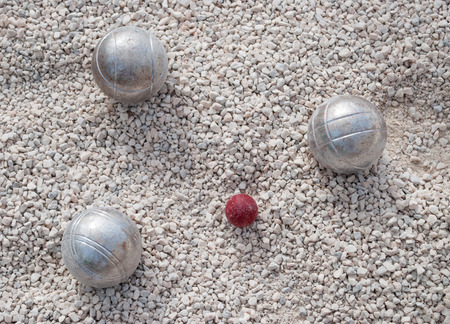 Metallic petanque balls and a small red jack on fine gravelの写真素材