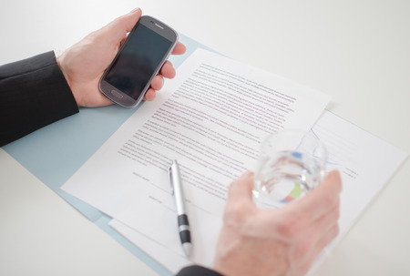 Businessman s hands with smartphone at the officeの写真素材