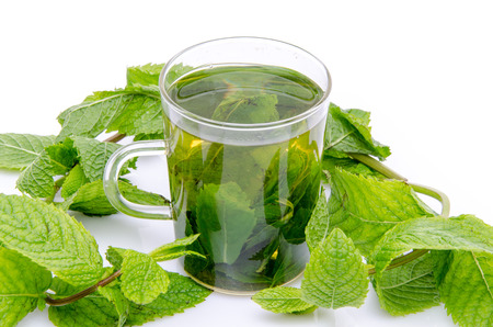 Cup of mint tea in the middle of fresh mint, isolated on white