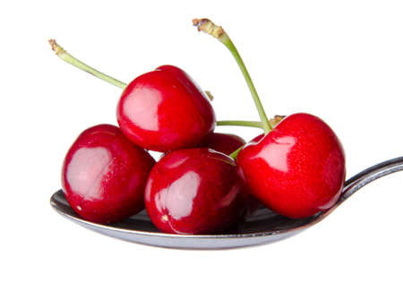 Fresh red cherries on a spoon, isolated on whiteの写真素材