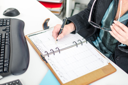 Businesswoman in office noting an appointment in her diaryの写真素材