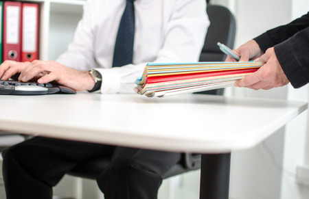 Secretary putting records on the desk of a businessman