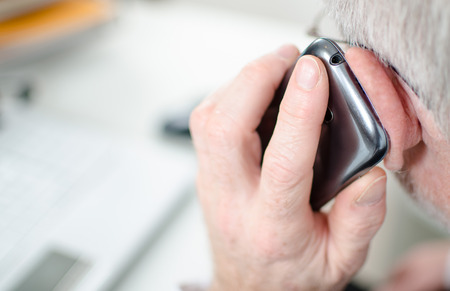 Hand holding a mobile phone to his ear, closeup