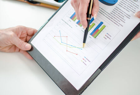 Assistant showing graphs to her boss at officeの写真素材