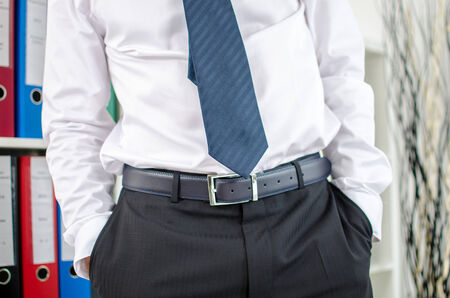 Business man standing with his hands in pockets at officeの写真素材
