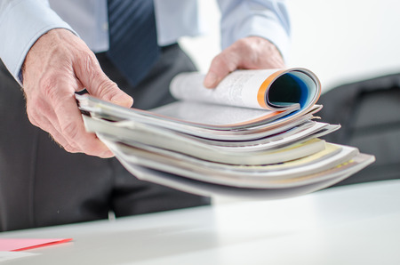 Businessman holding magazines at officeの写真素材