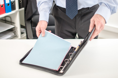 Businessman taking folder from his briefcase at officeの写真素材