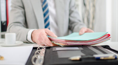 Businessman at office with folders and a coffeeの写真素材