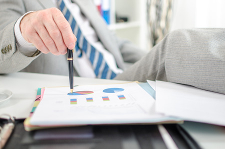 Relaxed businessman checking financial graphs at officeの写真素材