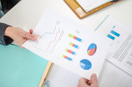 Assistant showing graphs to her boss at office