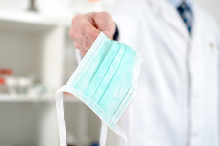 Doctor holding a surgical mask in his officeの写真素材