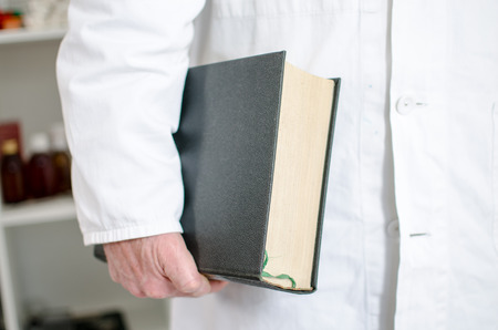 Doctor holding a medical book under his arm in his officeの写真素材