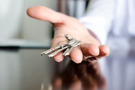 Estate agent showing house keys on a wooden tableの写真素材
