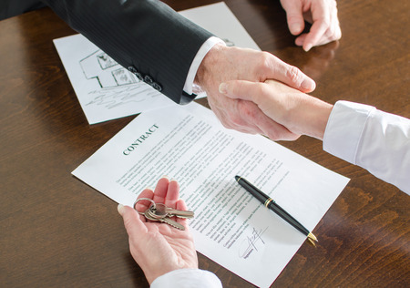 Estate agent shaking hands with his customer after delivering the house keysの写真素材