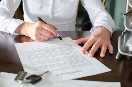 Woman signing a car purchase contract in car dealership